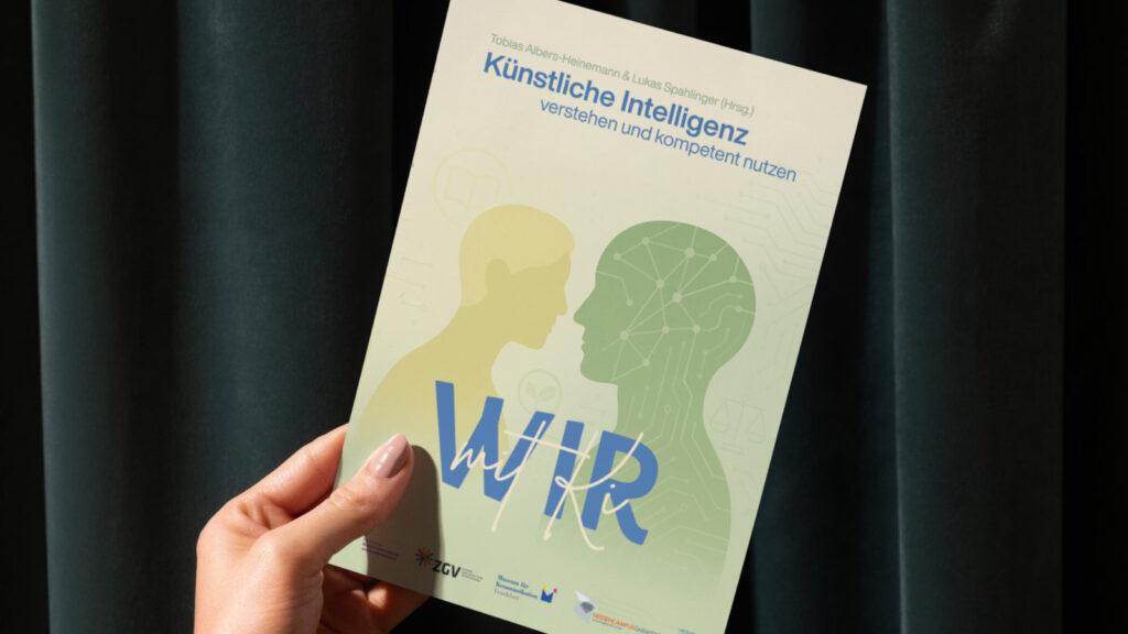 Eine Hand hält das Buch Wir mit KI