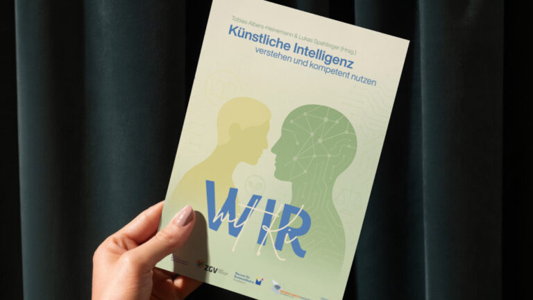 Eine Hand hält das Buch Wir mit KI